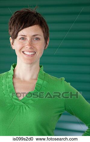 Stock Image - Woman against green background, portrait. Fotosearch