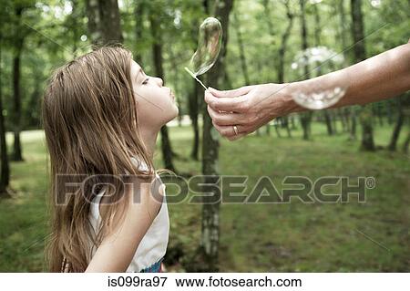 Stock Photo - Woman holding bubble wand, girl blowing bubble. Fotosearch