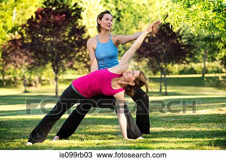 Stock Image - Yoga instructor and student in park. Fotosearch