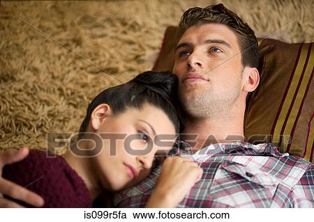 Stock Image - Young couple lying on floor. Fotosearch
