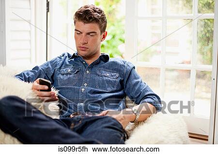 Stock Image - Young man holding smartphone. Fotosearch