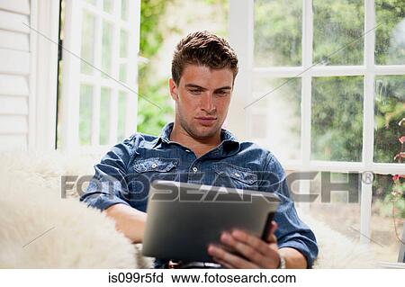 Stock Image - Young man with digital tablet. Fotosearch