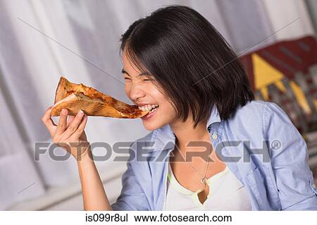 Young woman biting a slice of pizza View Large Photo Image Stock Image - Young woman biting a slice of pizza. Fotosearch