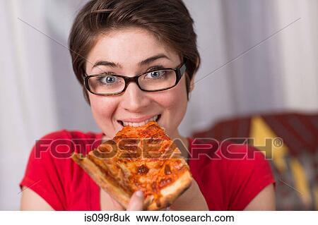 Stock Image - Young woman eating a slice of pizza. Fotosearch