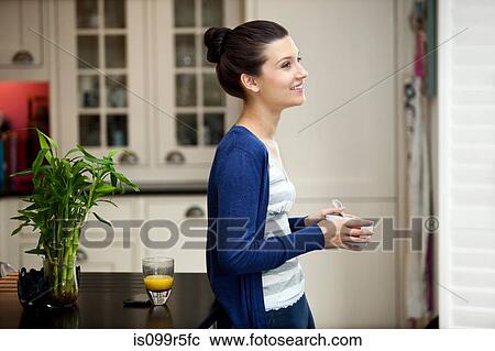 Stock Image - Young woman eating breakfast. Fotosearch