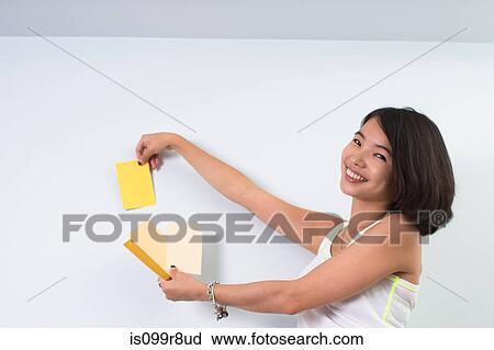 Young woman holding up color swatches to wall View Large Photo Image Stock Image - Young woman holding up color swatches to wall. Fotosearch