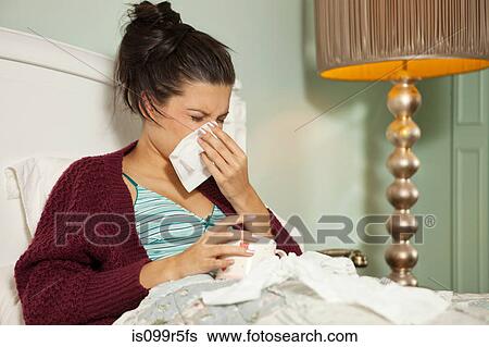 Stock Photograph - Young woman in bed with cold. Fotosearch