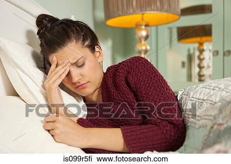 Young woman in bed with headache View Large Photo Image Stock Image - Young woman in bed with headache. Fotosearch