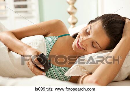 Stock Photo - Young woman in bed with smartphone. Fotosearch