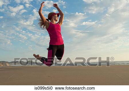 Young woman jumping in the air on beach View Large Photo Image Stock Image - Young woman jumping in the air on beach. Fotosearch
