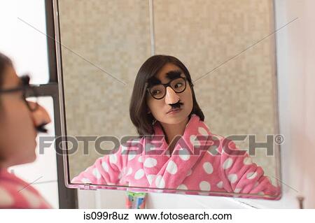Young woman looking herself wearing funny disguise View Large Photo Image Stock Photo - Young woman looking herself wearing funny disguise. Fotosearch