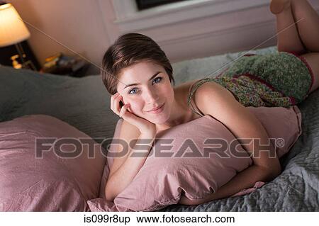 Young woman lying on her bed, holding pillow View Large Photo Image Stock Photography - Young woman lying on her bed, holding pillow. Fotosearch
