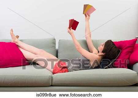 Young woman lying on sofa, looking at color swatches View Large Photo Image Stock Image - Young woman lying on sofa, looking at color swatches. Fotosearch
