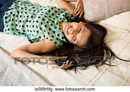 Young woman on bed with smartphone, high angle View Large Photo Image Stock Image - Young woman on bed with smartphone, high angle. Fotosearch