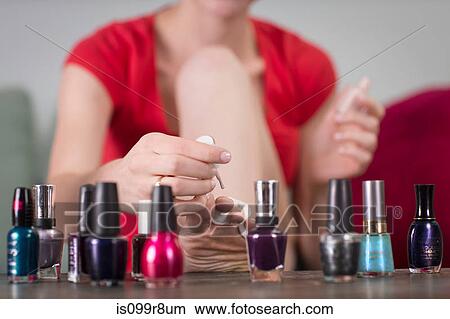 Picture - Young woman painting her toenails. Fotosearch