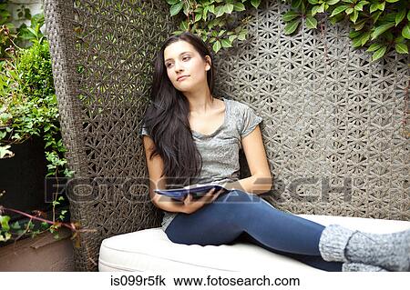 Young woman relaxing on bench in garden View Large Photo Image Stock Image - Young woman relaxing on bench in garden. Fotosearch