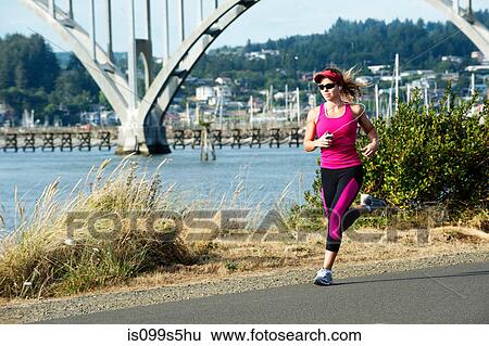 Stock Photograph - Young woman running on path near the sea. Fotosearch