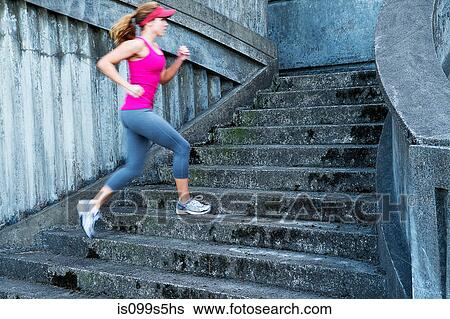 Stock Photograph - Young woman running up stairs. Fotosearch