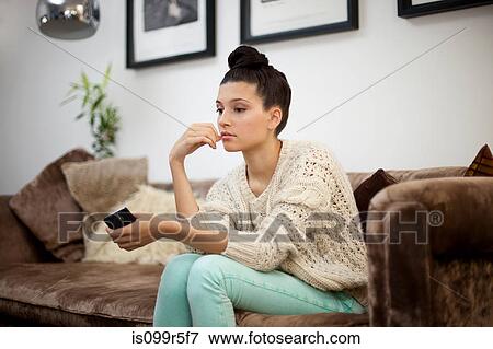 Stock Photo - Young woman sitting on sofa with smartphone. Fotosearch