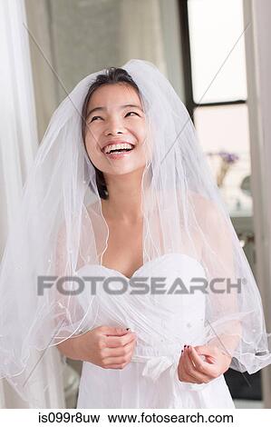 Stock Photo - Young woman wearing wedding dress and laughing. Fotosearch