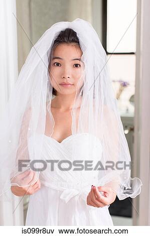 Stock Photo - Young woman wearing wedding dress with veil. Fotosearch