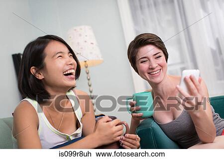 Young women looking at smartphone and laughing View Large Photo Image Stock Image - Young women looking at smartphone and laughing. Fotosearch