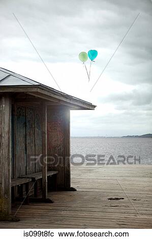 Stock Image - Balloons floating by old seaside shelter, Flensburg, Germany. Fotosearch