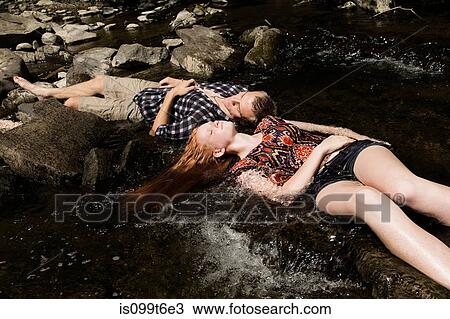 Stock Image - Couple lying down in river. Fotosearch