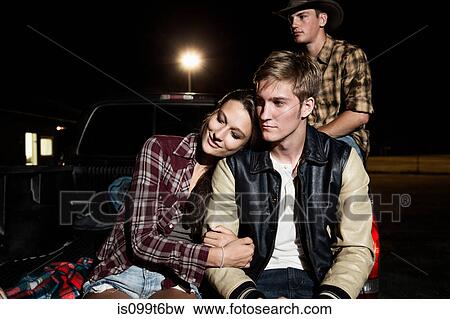 Couple sitting on tailgate of car at night View Large Photo Image Stock Photo - Couple sitting on tailgate of car at night. Fotosearch