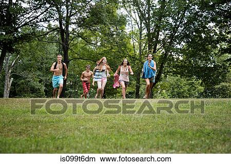 Picture - Five friends running on grass, front view. Fotosearch