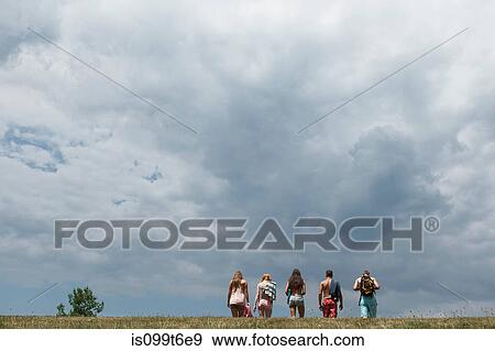 Stock Photo - Five friends walking in field, rear view. Fotosearch