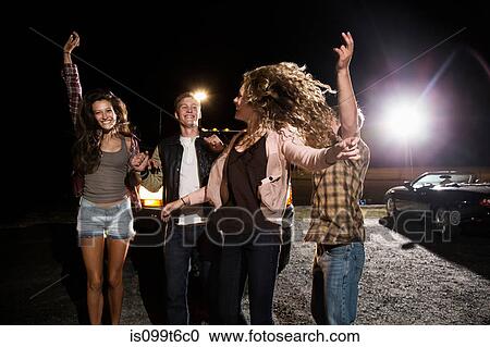 Four friends in parking lot at night View Large Photo Image Stock Image - Four friends in parking lot at night. Fotosearch