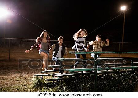 Four friends walking over bleachers at night View Large Photo Image Stock Image - Four friends walking over bleachers at night. Fotosearch