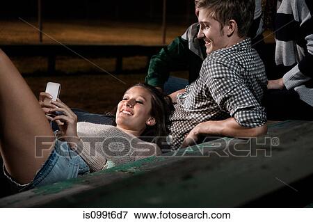 Friends on bleachers at night, girl using cell phone View Large Photo Image Stock Photo - Friends on bleachers at night, girl using cell phone. Fotosearch