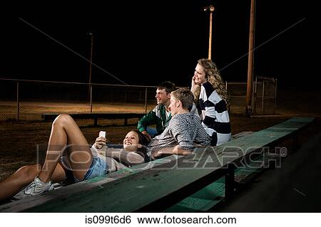 Friends on bleachers at night, girl using cell phone View Large Photo Image Stock Photograph - Friends on bleachers at night, girl using cell phone. Fotosearch