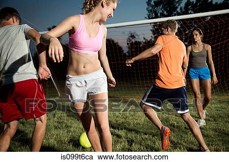 Stock Image - Friends playing soccer at night. Fotosearch