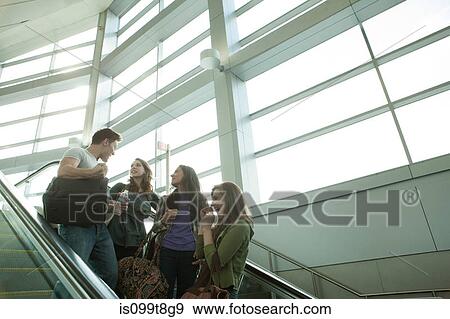 Stock Photo - Friends travelling on escalator. Fotosearch