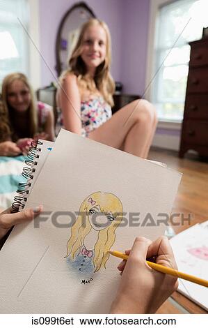 Girl drawing portrait of friend on notebook View Large Photo Image Stock Photograph - Girl drawing portrait of friend on notebook. Fotosearch