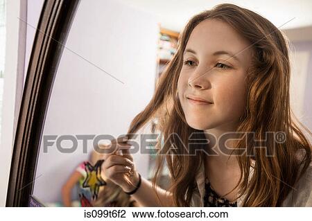 Girl looking in mirror, touching hair View Large Photo Image Stock Image - Girl looking in mirror, touching hair. Fotosearch