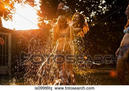 Stock Photography - Girl pouring bucket of water over friend's head. Fotosearch