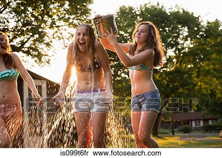 Girl pouring bucket of water over friend's head View Large Photo Image Stock Photography - Girl pouring bucket of water over friend's head. Fotosearch