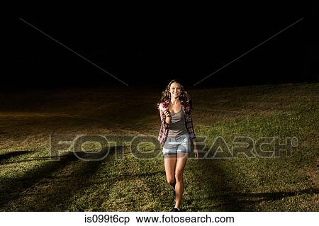 Stock Photography - Girl walking on grass holding sparkler. Fotosearch