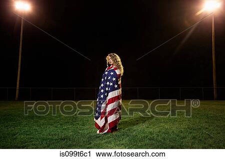 Stock Image - Girl wrapped in american flag at night. Fotosearch