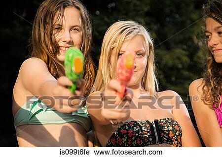 Stock Image - Girls aiming water pistols at camera. Fotosearch