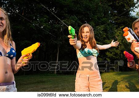 Stock Image - Girls having water fight with water pistols. Fotosearch