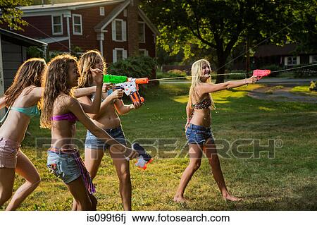 Stock Image - Girls having water fight with water pistols. Fotosearch