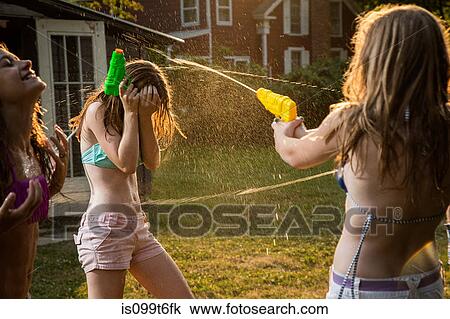 Stock Image - Girls having water fight with water pistols. Fotosearch