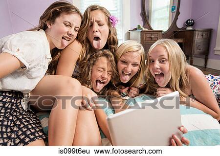 Girls looking at digital tablet, sticking out tongues View Large Photo Image Stock Photograph - Girls looking at digital tablet, sticking out tongues. Fotosearch
