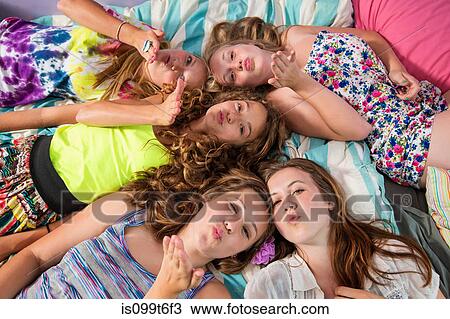 Stock Image - Girls lying on bed, blowing kisses. Fotosearch