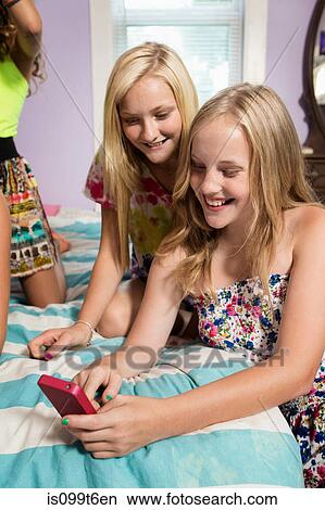 Girls using smartphone in bedroom View Large Photo Image Picture - Girls using smartphone in bedroom. Fotosearch